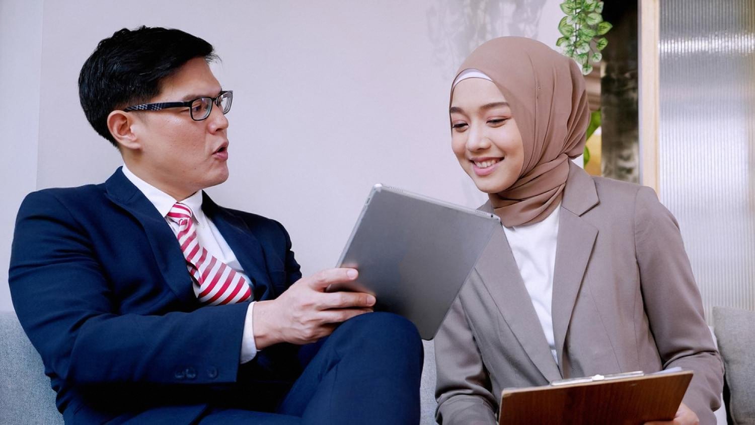 Hotel staff member showing a guest her online check-in details on a tablet at reception